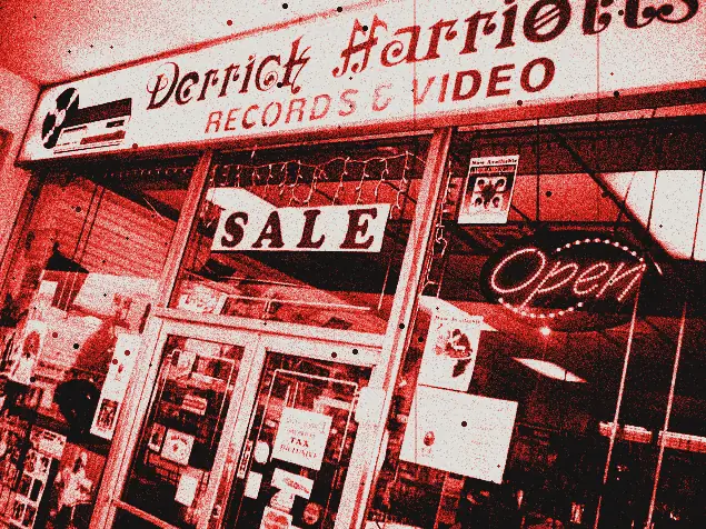 Vetrina di un negozio di dischi con l'insegna «Derrick Harriott's Records & Video», il cartello SALE e la scritta luminosa Open