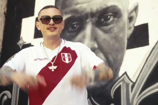Кадр из клипа Amore puro: тёмные очки и бело-красная футболка сборной Перу на фоне большого мурала